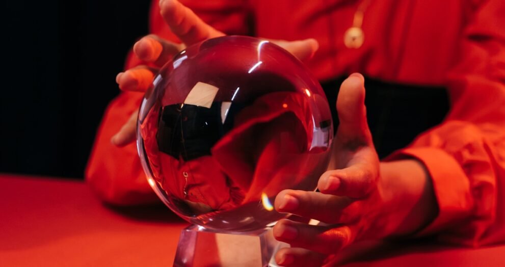 cropped view of blurred fortune teller predicting near crystal ball isolate on black, banner