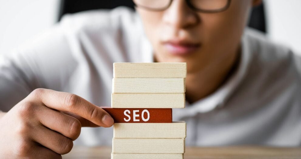 selective focus of asian seo manager holding wooden rectangle with lettering seo